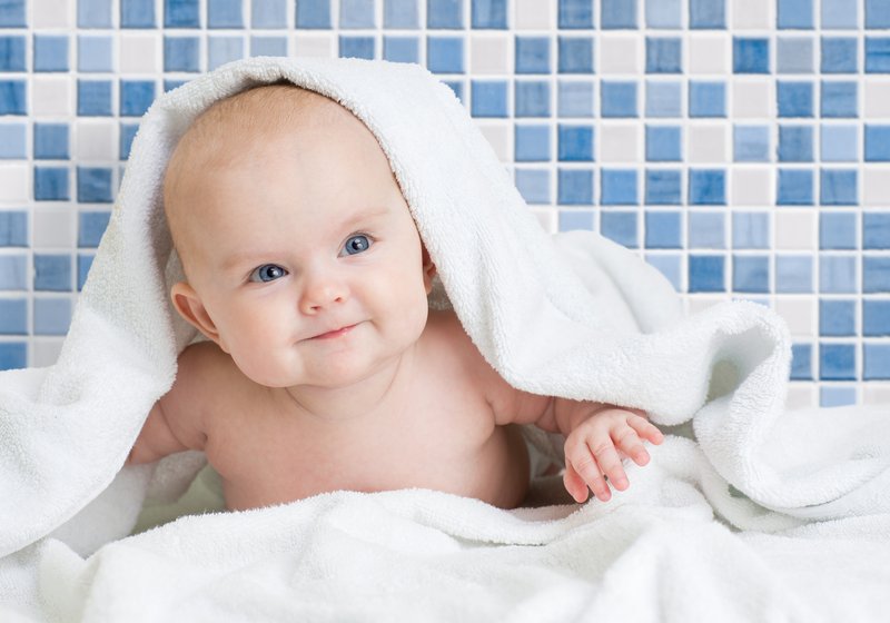 Smiling baby wrapped in a white towel